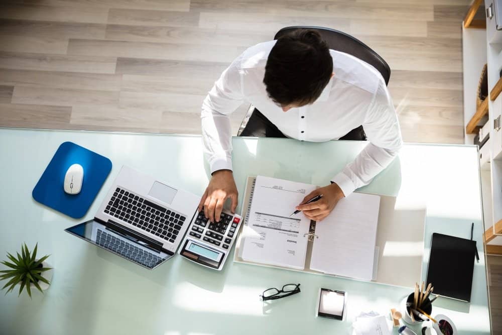 Above,View,Of,Young,Businessman,Calculating,Invoice