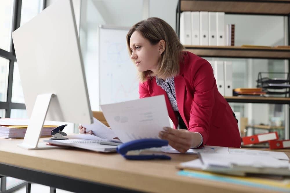 Focused,Woman,Compares,Paper,Accounting,Documents,With,Computer,Version,Standing