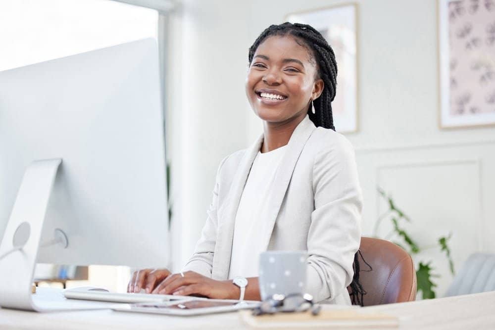 Happy,,Portrait,Of,Businesswoman,Typing,And,Computer,At,Her,Desk