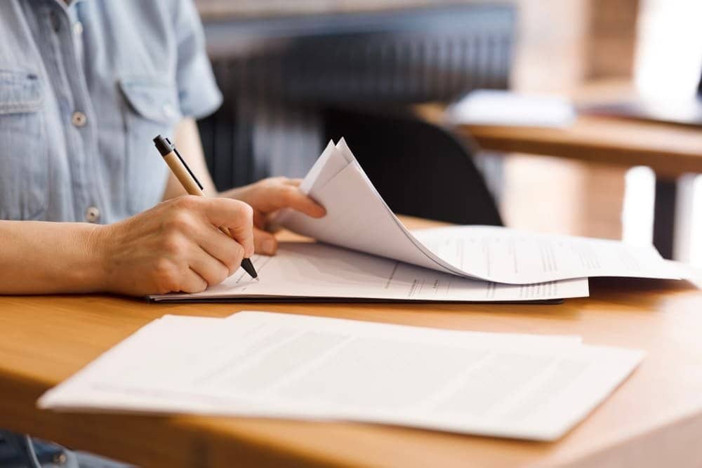 Female,Hands,With,Pen,Signing,Documents,,Business,Papers,On,Wooden